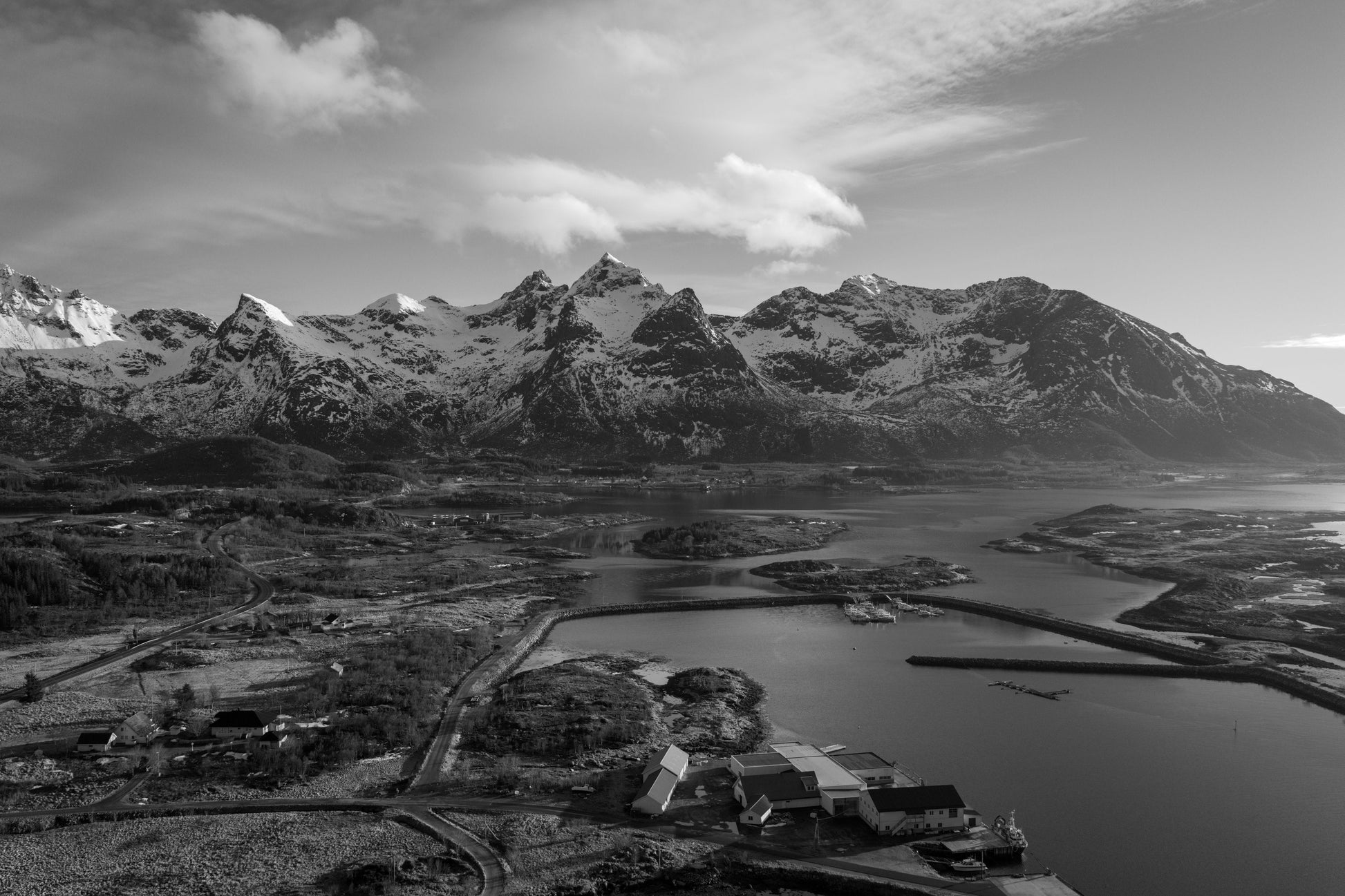 Aerial drone view of Reine harbor with red houses under overcast sky, Lofoten Norway