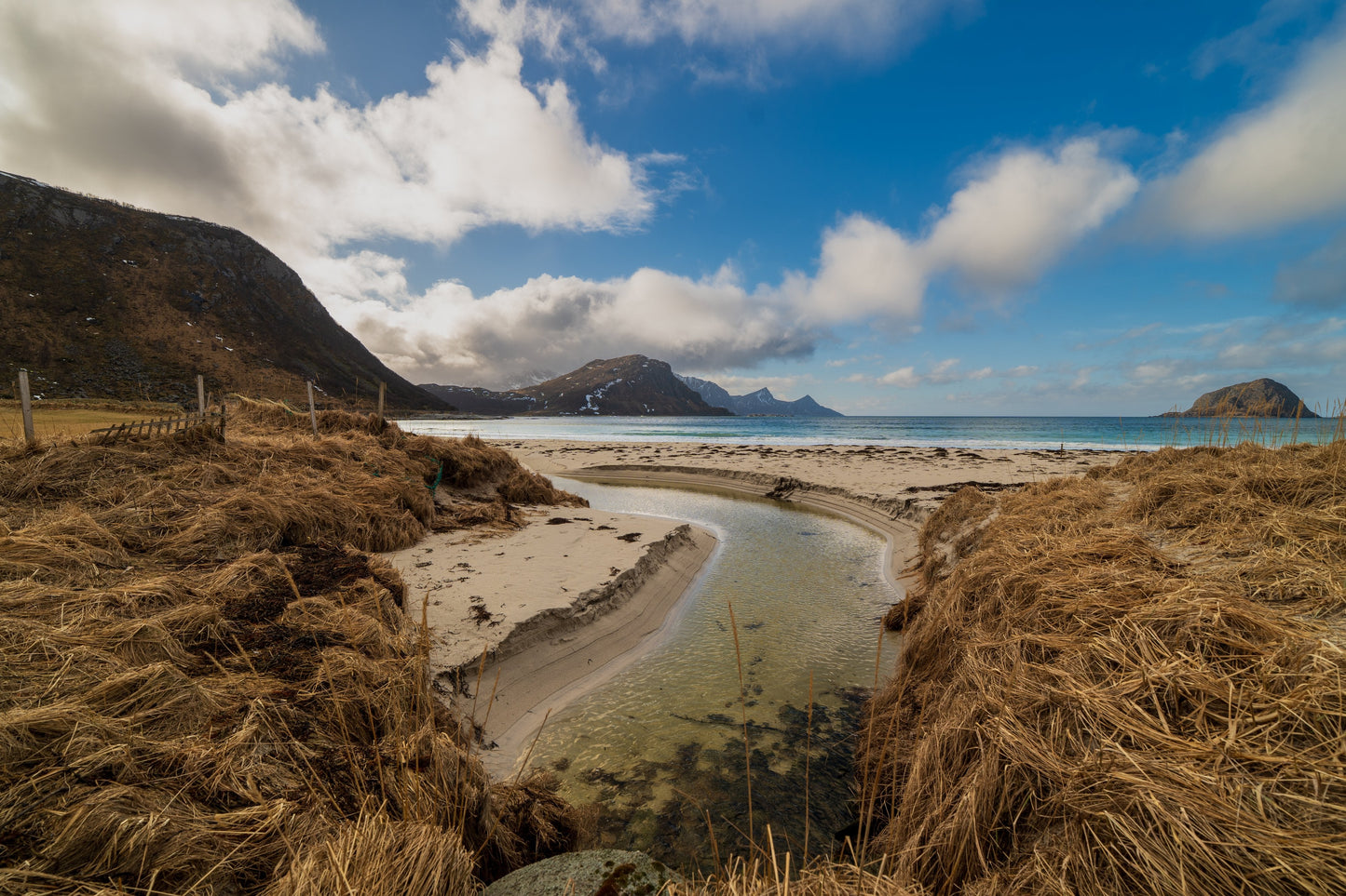 Stream flowing through sand dunes toward the sea on a Lofoten beach, Norway