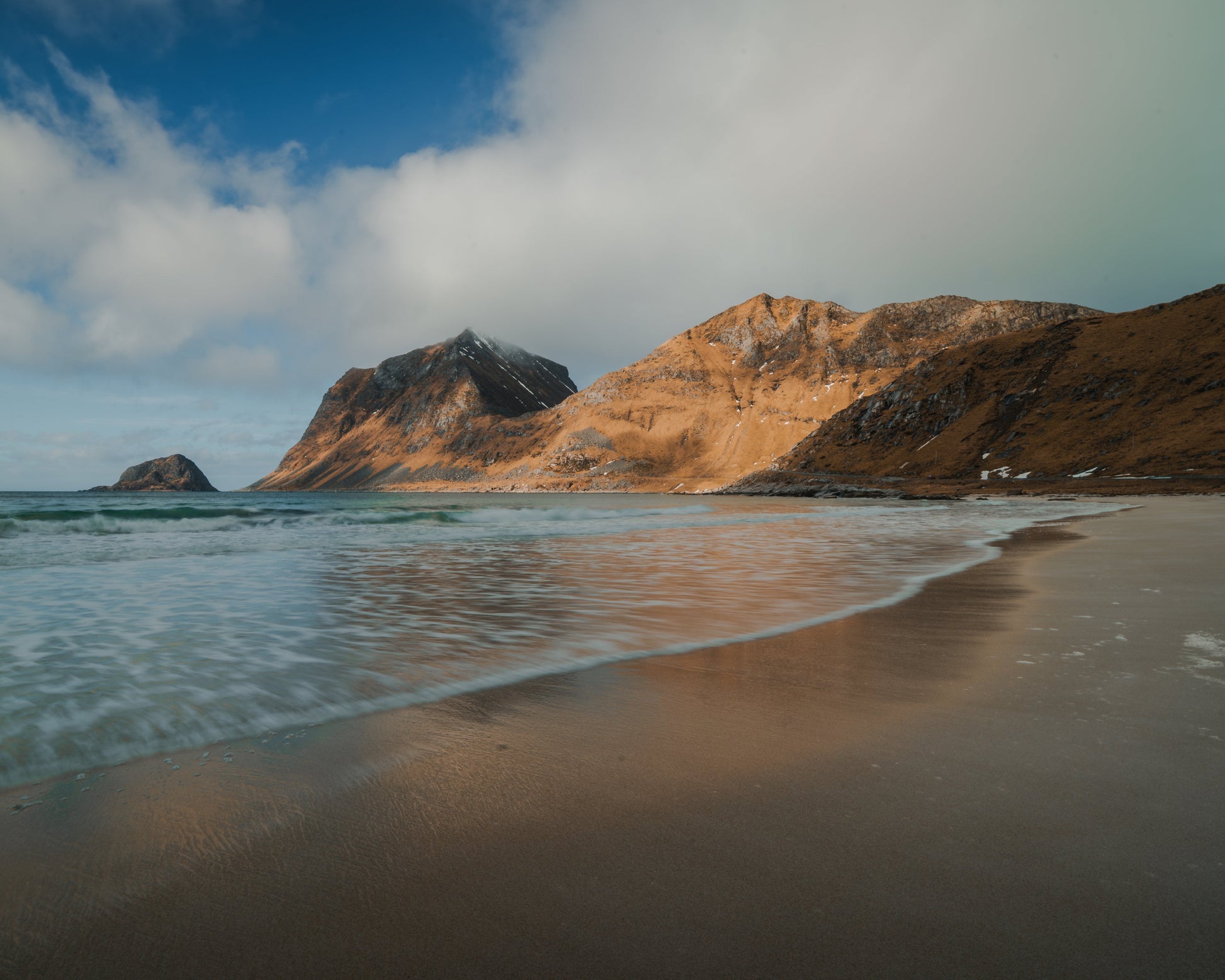 Waves washing over golden sand at Unstad Beach, Lofoten Norway