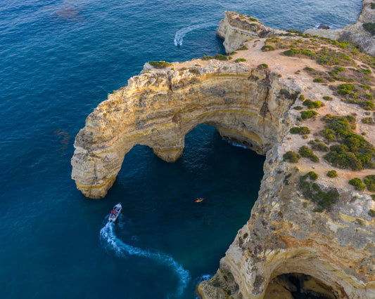 Aerial view of Benagil limestone arch with tour boat, Algarve, Portugal