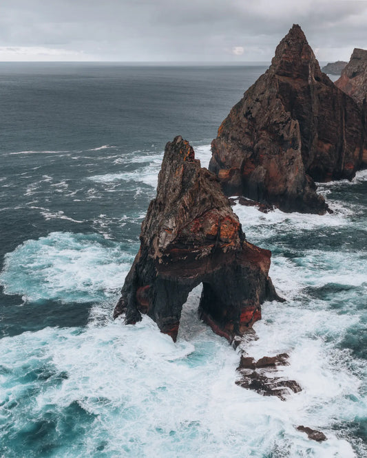 Volcanic sea arch with crashing waves at Ponta do Rosto, Madeira, Portugal
