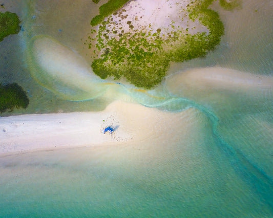 Aerial view of white sandbar with blue umbrella and turquoise lagoon water, Tavira, Algarve, Portugal