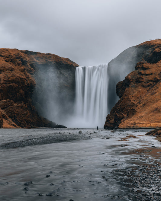 Skógafoss waterfall with lone figure at base, Iceland