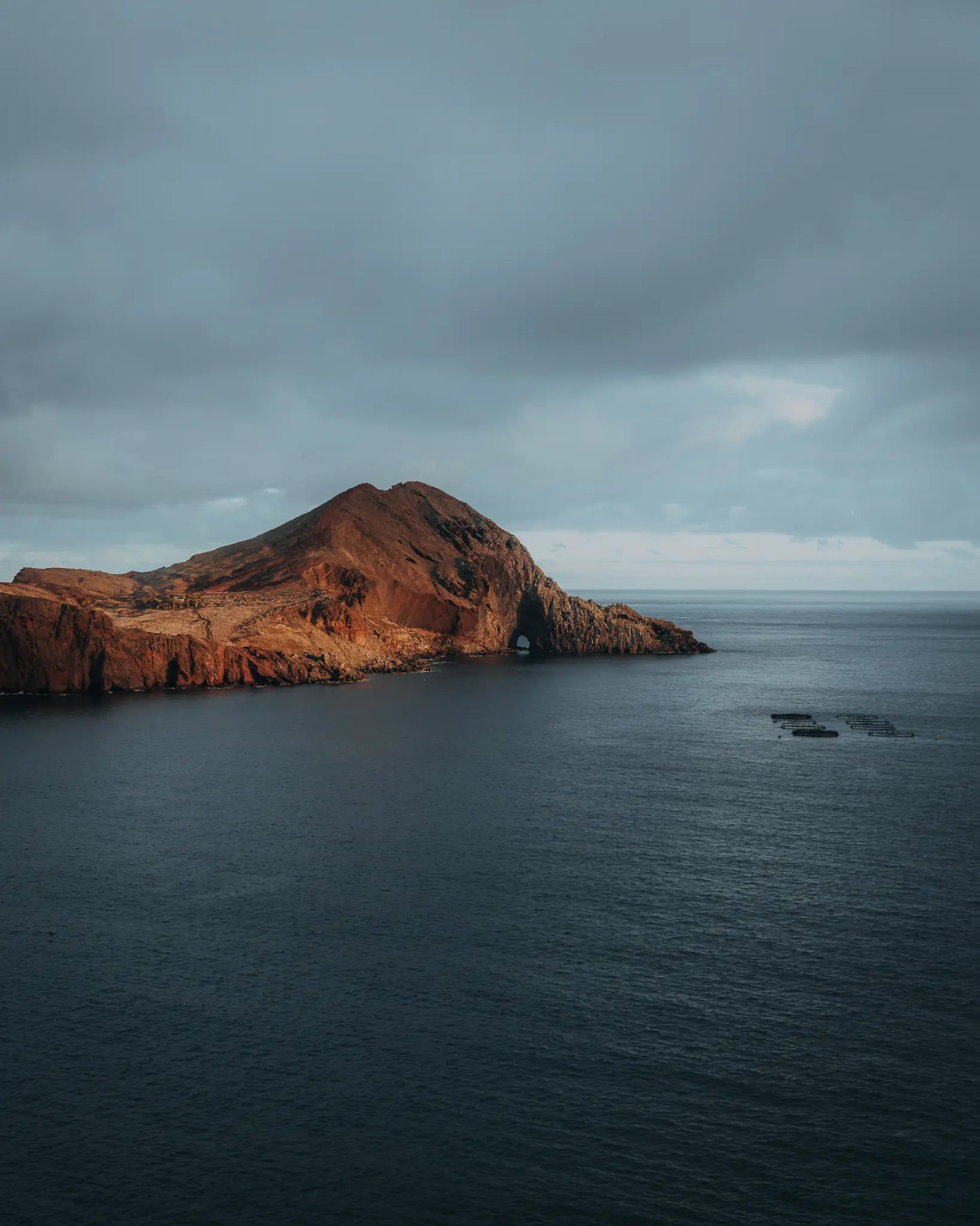 Volcanic headland with sea arch in warm afternoon light, Madeira, Portugal