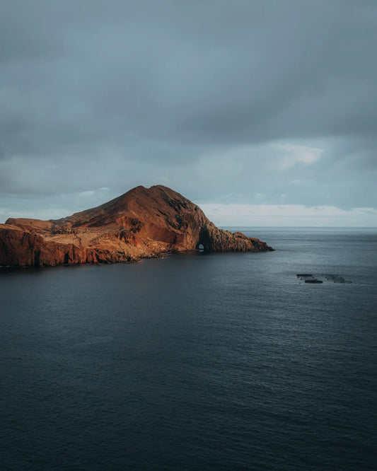 Volcanic headland with sea arch in warm afternoon light, Madeira, Portugal