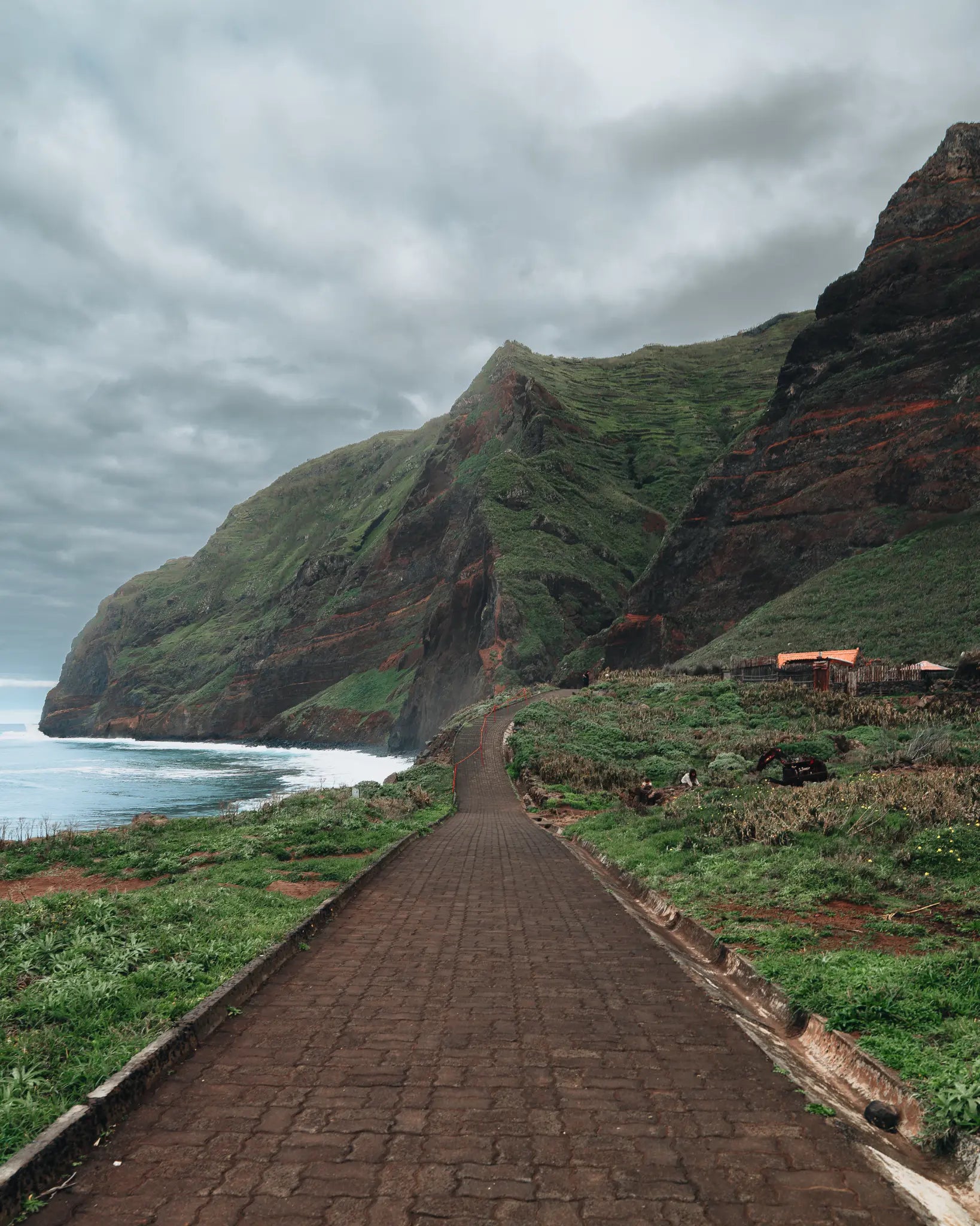 Stone path leading to green volcanic cliffs on Madeira north coast, Portugal