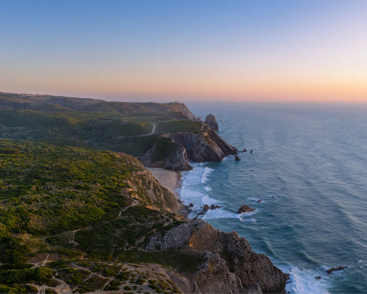 Aerial view of Praia da Adraga coastline at sunset with rock stacks, Sintra, Portugal